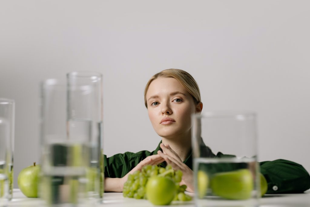 woman with apple cider vinegar glasses and apples