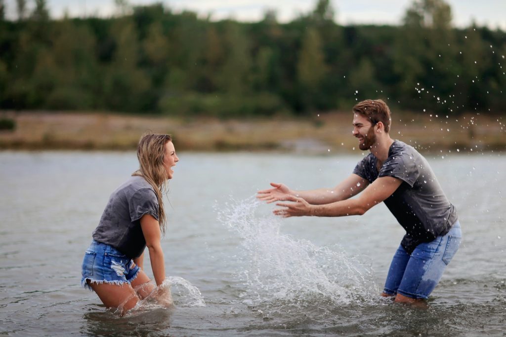 Libra man and Gemini woman smiling and playing with water